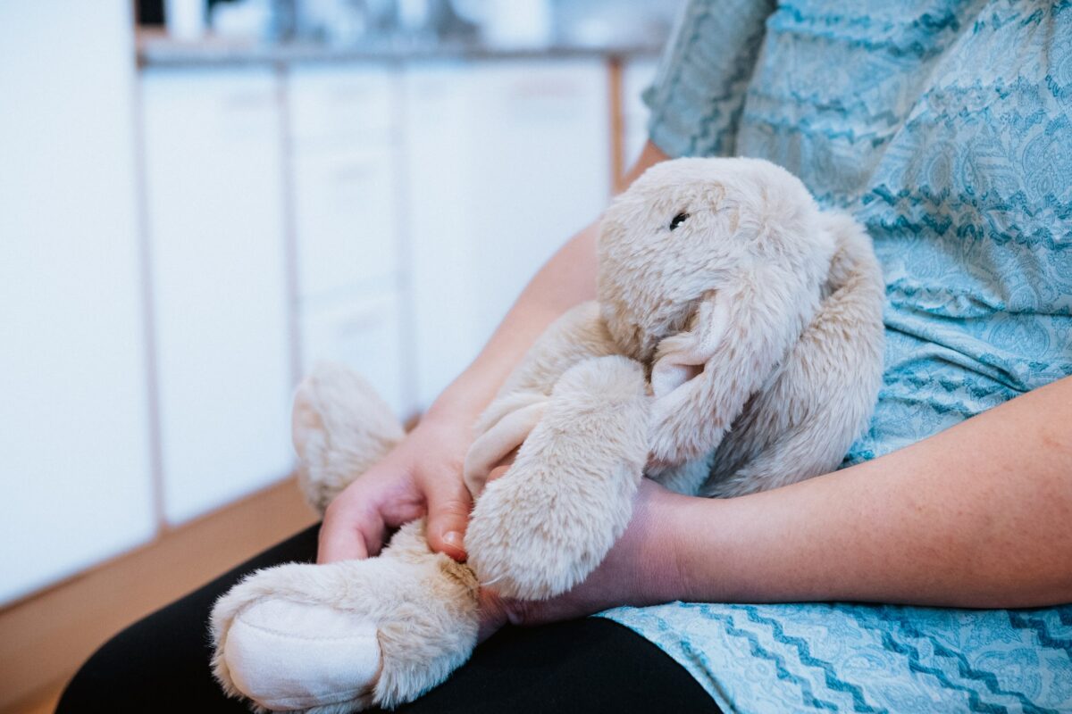 Kind hält grauen Stoffhasen in den Händen